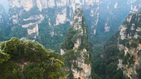 Aerial-flying-close-to-the-top-of-the-mountain-peaks-in-Zhangjiajie-National-Park-in-Wulingyuan,-Hunan,-China,-featuring-the-renowned-Karst-Mountains---the-Avatar-Hallelujah-Mountains