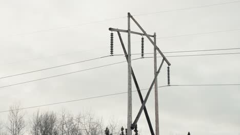 Slow-Close-Up-Overcast-Panning-Shot-Large-Wooden-Electricity-Network-Phone-Transmission-Tower-Electrical-Pylon-Carrying-High-Voltage-Current-Long-Distances-Outdoor-Environment-Power-Infrastructure