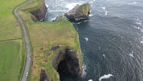 Coastline-with-green-cliffs-and-winding-road-by-the-sea-at-Kilkee-Cliffs,-Ireland