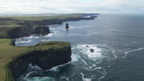 Kilkee-Klippen-In-Irland-Mit-üppigem-Grün-Und-Meereswellen,-Die-Gegen-Felsen-Krachen