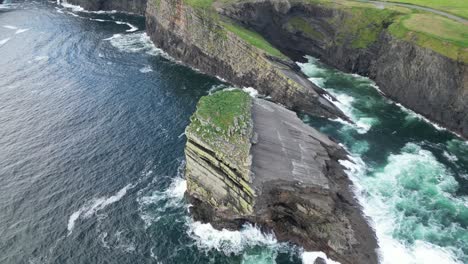 Kilkee-Cliffs-in-Ireland-with-waves-crashing-against-rugged-coastline,-aerial-view