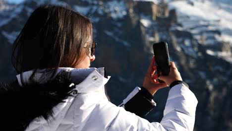 Female-tourist-in-Switzerland-hold-phone-and-take-photos-of-nature-landscape