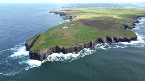Rugged-coastline-with-a-lighthouse,-cliffs-and-waves-crashing-against-rocks,-aerial-view