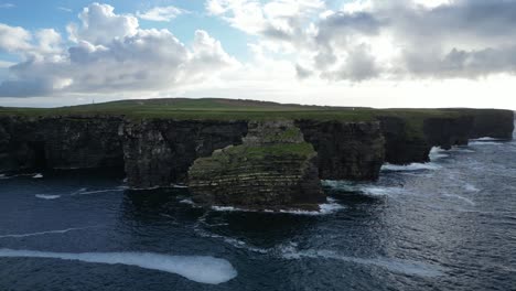 Majestic-Kilkee-Cliffs-in-Ireland-with-rolling-waves-and-lush-greenery,-aerial-view