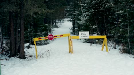 A-Static-4K-Shot-of-a-Winter-Snow-Covered-Fall-Evergreen-Forest-Pisew-Falls-Federal-Park-Roadway-Hiking-Back-Country-Trail-Path-Closed-by-Yellow-blockers-For-Season-Stop-Sign-No-Entry