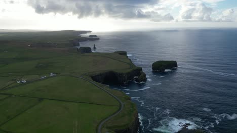 Cliffs-by-the-sea-with-sun-peering-through-clouds,-Ireland,-aerial-view