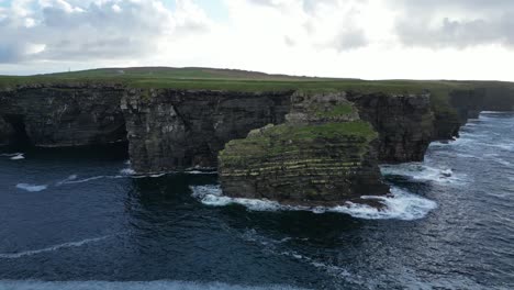 Majestic-Kilkee-Cliffs-meeting-the-Atlantic-Ocean-with-waves-crashing,-aerial-view