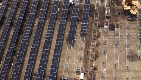 Aerial-drone-view-Drone-camera-shows-men-taking-solar-panels-out-of-boxes-and-lining-them-up
