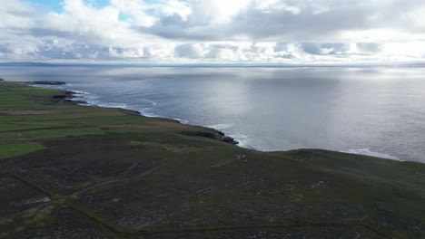 Loophead-lighthouse-and-coastline,-with-expansive-sea-and-cloudy-skies,-aerial-view