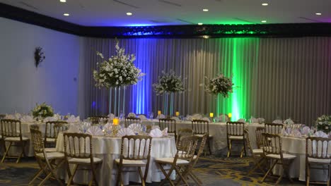 Colorful-and-elegant-meeting-room-in-a-hotel,-decorated-for-a-wedding-reception-celebration,-round-tables-with-tall-centerpieces-with-Gypsophila-paniculata-flowers-and-white-roses