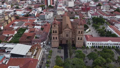 Catholic-basilica-and-central-square-in-Bolivia-city,-aerial-orbits