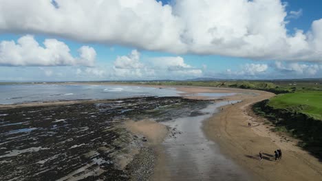 Bahía-Doughmore-Con-Una-Extensa-Playa,-Aguas-Azules-Y-Un-Campo-Verde-Bajo-Un-Cielo-Lleno-De-Nubes,-Vista-Aérea