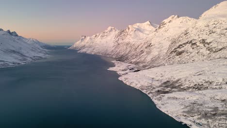Ruhiger,-Verschneiter-Fjord-Bei-Sonnenuntergang-Mit-Bergen,-Die-Sich-Auf-Ruhigem-Wasser-Spiegeln