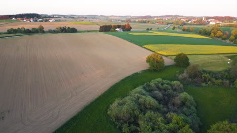 Drone-journey-toward-a-colorful-scene-featuring-trees,-fields,-cultivated-lands