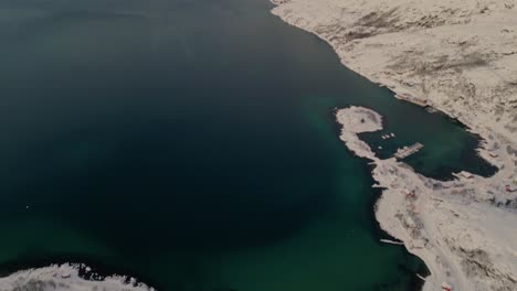 Panorama-Luftaufnahme-Von-Einem-Schneebedeckten-Küstendorf-Bis-Zum-Wunderschönen-Smaragdgrünen-Wasser-Der-Fjorde