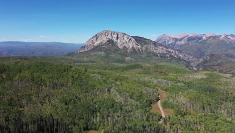 Slow-pan-in-Aerial-view-of-Marcellina-Mountains-south-face-near-Crested-Butte-Colorado-during-a-clear-fall-day-with-dirt-road-below