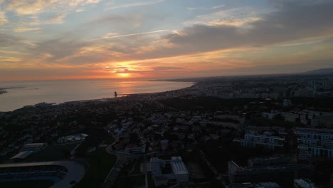 Luftaufnahme-Eines-Rot-orangefarbenen-Sonnenuntergangs-über-Lissabon,-Portugal,-Mit-Einer-Fülle-Von-Wolken,-Die-Dem-Lebendigen-Abendhimmel-Tiefe-Und-Textur-Verleihen
