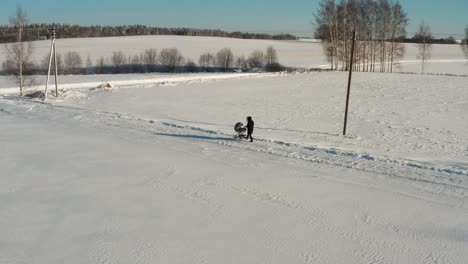 Single-mother-walk-on-countryside-road-with-baby-carriage,-winter-landscape