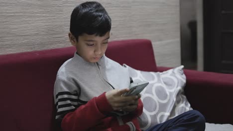young-kid-watching-mobile-and-playing-online-game-at-home-at-night-from-different-perspective