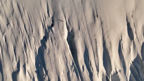 Aerial-top-view-over-a-person-standing-on-Sólheimajökull-glacier-textured-ice,-in-Iceland