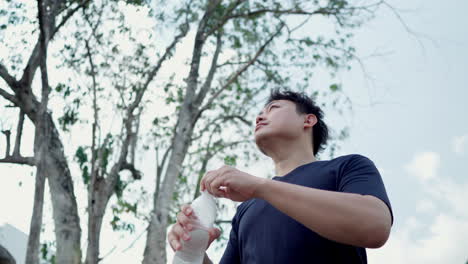 Man-drinking-water-from-a-plastic-bottle-water-after-workout-in-forest