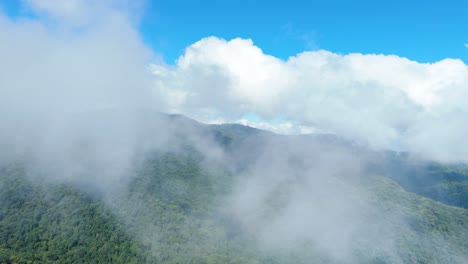 Looking-out-of-the-Window-and-Flying-Through-the-Clouds,-Amazing-Fluffy-Cloudscape-with-Beautiful-Forest-Mountains-and-Blue-Sky,-Forest-Conservation-Area-Evergreen-Forest