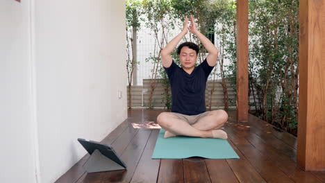 Asiatischer-Mann-Praktiziert-Achtsame-Yoga-Meditationsübung-Mit-Online-Anleitung-Auf-Dem-Tablet