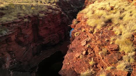 Woman-in-the-desert-standing-on-the-edge-of-the-cliff-in-Karijini-in-Western-Australia,-aerial-orbital