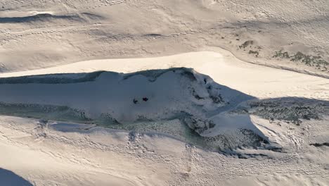 Aerial-top-view-over-many-people-hiking-on-Sólheimajökull-glacier,-in-Iceland,-at-dusk