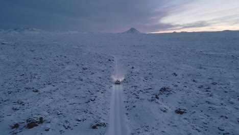 Driving-through-snowy-mysterious-volcanic-land-towards-mountain,-Iceland