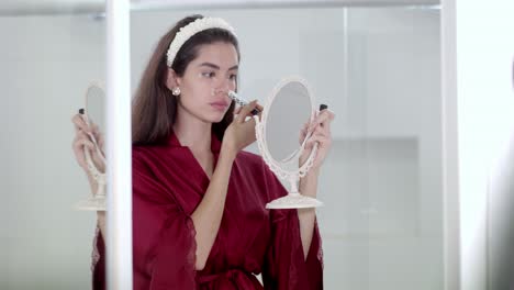 Das-Model-Nutzt-Im-Rahmen-Ihrer-Routine-Sorgfältig-Make-up-Accessoires-Und-Einen-Spiegel