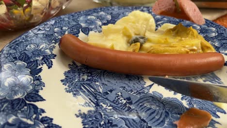 Eating-typical-German-bockwurst-sausage-and-homemade-potato-salad-close-up-personal-perspective