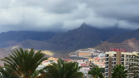 Niebla-Sobre-Montañas-Destacadas,-Isla-Tropical-Con-Palmera-Tenerife