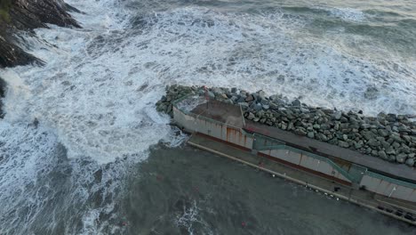 Huge-foamy-sea-waves-breaking-on-harbor-wave-breaker-pier-in-Genoa