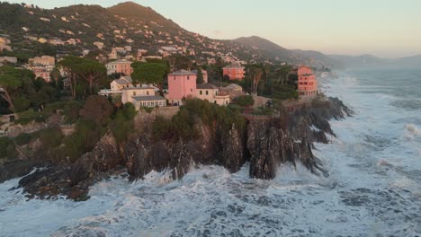Forceful-sea-waves-breaking-on-jagged-coast-with-houses-in-Genoa-city