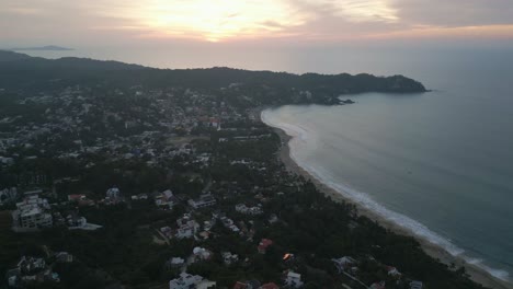 Ocean-waves-crash-on-long-sandy-stretch-with-coastal-view-homes-in-Sayulita-Mexico