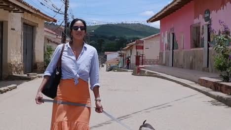 Latina-in-orange-dress-walks-dog-on-quaint-street-in-Samaipata-Bolivia