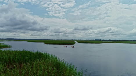 Panoramaaufnahme-Einer-Gruppe-Von-Kanus,-Die-In-Ruhigen-Flussgewässern-Paddeln,-Drohnenlandschaft-Aus-Der-Luft