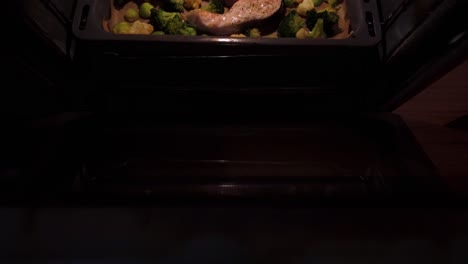 Footage-of-delicious-raw-Salon-cutlets-in-a-baking-tray-along-with-some-vegetables-,-cooking-in-an-oven