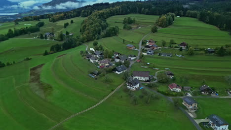 Picturesque-village-on-green-field-hillside-in-alpine-countryside