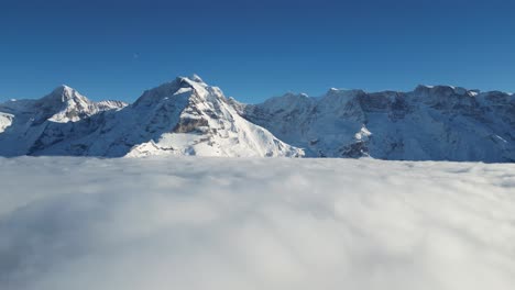 Dense-cloudscape-near-snowy-Switzerland-mountain-range-with-blue-sky-day