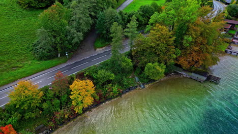 White-car-drives-Road-next-to-lake-green-European-countryside-summer-Aerial-Trip