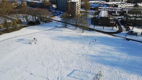 Aerial-of-kids-playing-in-a-snow-covered-park