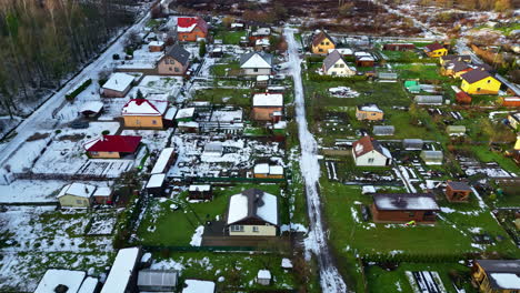 Aerial-Drone-Fly-Above-Town-of-low-houses,-Neighborhood,-Snowed-Roads,-Gardens