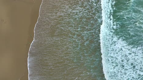 Aerial-Of-Foamy-Sea-Water-Rolling-On-Sandy-Coast---Drone-Shot