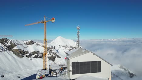 Edificio-Y-Grúa-Torre-Cerca-Del-Borde-Nevado-Del-Complejo-De-Montaña-De-Suiza