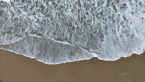 Luftaufnahmen-Von-Schäumenden-Meereswellen,-Die-Auf-Den-Strand-Treffen---Zeitlupe