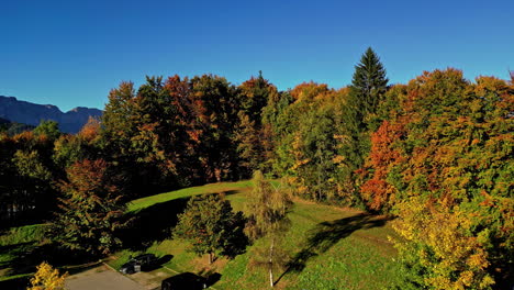 Aerial-view-of-a-parking-lot-in-middle-of-vibrant-foliage-trees,-sunny-fall-day-in-Austria