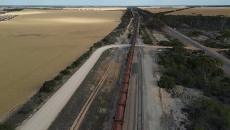 Descending-drone-shot-showing-industrial-train-on-track-in-suburb-area-of-Western-Australia