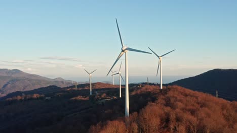 Green-energy-production-by-wind-turbines-spinning-on-mountain-top,-aerial-view